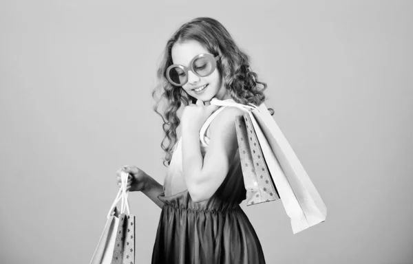 Giornata dello shopping. Bambino moda ragazza occhiali da sole tenere pacchetto. Marchio di bambini preferito. Ragazza con la borsa della spesa. Shopping tour all'estero. Vendita stagione estiva. Shopping e acquisto. Venerdi 'nero. Sconto di vendita — Foto Stock