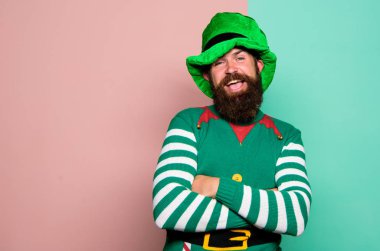 Noel elfi. Elf konsepti. Gelenekler ya da gelenekler. Mutlu kutlamalar. Sakallı elf. Kış karnavalı. Aziz Patrick Günü. Parti için yeşil kostüm giyen sakallı hippi. Neşeli adam bayramı kutluyor