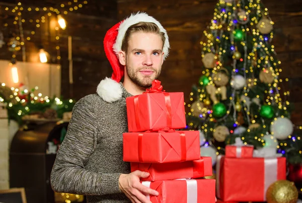 Veselý muž v červeném Santově klobouku. šťastný chlap miluje dárky. Zimní nákupy. oslavit nový rok doma. Vánoční dárek. Zdobit vánoční stromek. Poslední příprava. Každý dostane dárek. — Stock fotografie