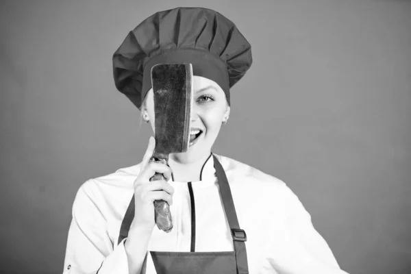 Mulher em chapéu de cozinheiro e avental. Carniceiro cortou carne. mulher feliz cozinhar comida saudável por receita. chef profissional na cozinha. Cozinha. Dona de casa com faca de cozinha. O chefe segura na faca. Empregada de mesa profissional — Fotografia de Stock