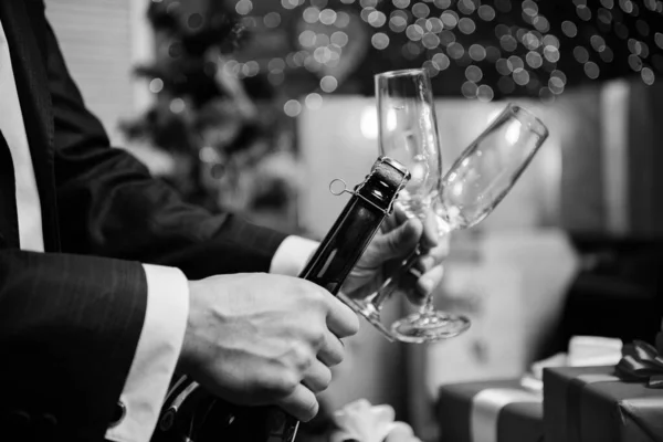 Open champagne and celebrate holiday. Celebrate new year with champagne drink. Toast and cheers concept. Lets celebrate. Male hands opening champagne bottle on christmas decorations background