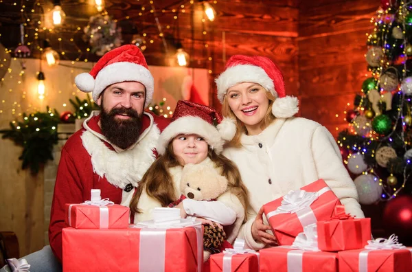 サンタ・ハットの小さな子供と両親。クリスマスプレゼント箱。プレゼントを開けなさい。メリー・クリスマス。父と母は娘を愛する。冬休みだ。新年がやって来ます。幸せな家族は新年を祝う — ストック写真