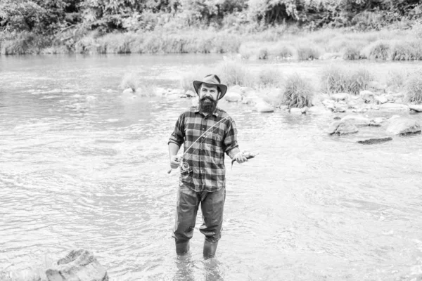 魚のフック。残忍な男は川の水の中に立っている。あごひげの漁師フィッシャー男性的な趣味。釣りは、注意深く、瞬間に完全に存在する必要があります。漁師の釣り道具。休息とレクリエーション — ストック写真
