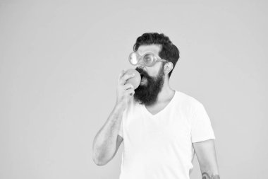 Taze ve sağlıklı. Sulu meyveler. Yaz beslenmesi. Yaz havasında sakallı hipster. Sarı arka planda turuncu güneş gözlüklü adam sakallı hipster. Olgun meyveli neşeli adam. Yaz tatili