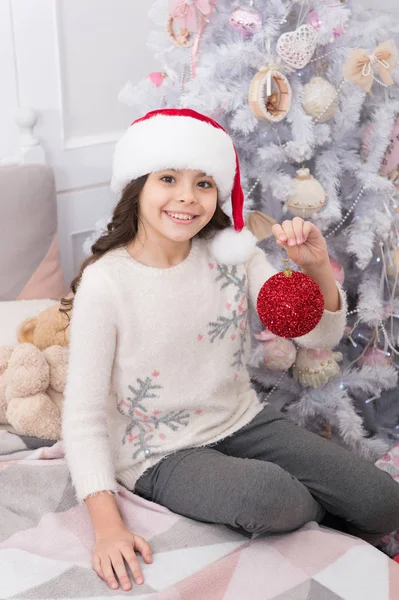 Choose pretty ball for your Christmas tree. Happy girl celebrate christmas and new year. Small child smile with new year santa look. New year party. Happy new year. Merry xmas. Holiday celebration — Stock Photo, Image