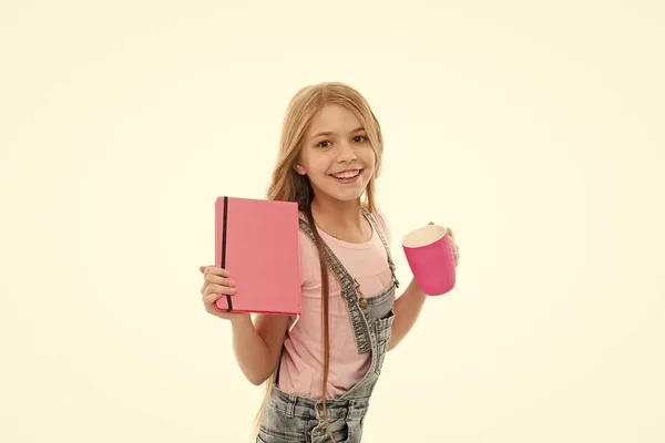 Menina bonito criança cabelo longo beber cacau ou chá. Estudante com livro ou bloco de notas e caneca tendo pausa para o chá. Conceito de balanço hídrico. A desfrutar de chá antes das aulas. Relaxe e recarregue. Bebida inspiradora — Fotografia de Stock