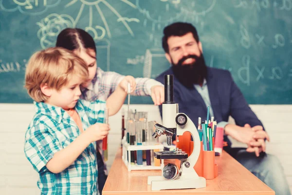 Estudantes que fazem experiências científicas com microscópio em laboratório. de volta à escola. Os miúdos da escola estudam ciências. crianças felizes. Miúdos a aprender química no laboratório da escola. Descobrindo cura — Fotografia de Stock