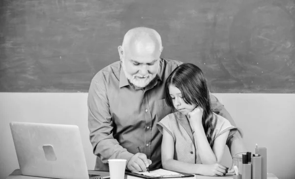 Modern knowledge. Modern education. Happy student. Senior teacher and girl at school lesson. Modern teaching method. Student girl with teacher man at blackboard. Schoolgirl and tutor with laptop