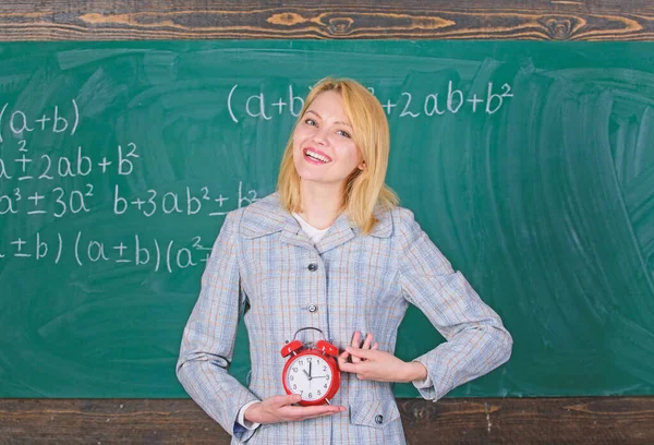 Lessons schedule. Welcome teacher school year. Experienced educator start lesson. What time is it. She cares about discipline. Woman teacher hold alarm clock. Girl formal wear school lecturer