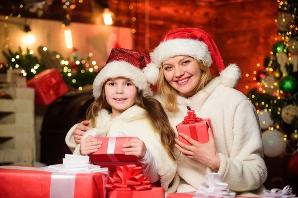 メリー・クリスマス。母と娘は休日が好きだ。クリスマスプレゼント箱。プレゼントを開けなさい。サンタ・ハットのお母さんと小さな子供の女の子。冬のショッピング販売。幸せな家族は新年を祝う — ストック写真