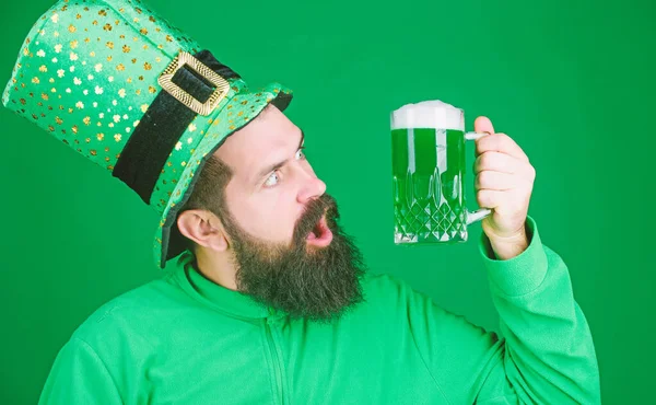 Celebrating saint patricks day in beer pub. Bearded man toasting to saint patricks day. Hipster in green leprechaun wear holding beer mug. Irish man with beard drinking green beer. Drinker by nature