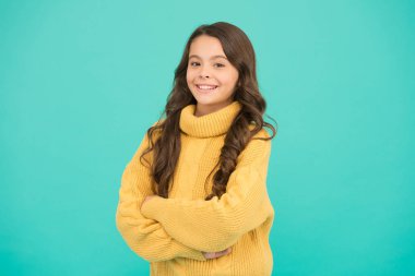 Moda çocuğu için moda tasarımı. Küçük kızın saf güzelliği. Çocuk sıradan kış modası tarzında. Çocuklar için örgü örüyorum. Mavi arka planda küçük bir kız. Uzun esmer saçlı küçük bir kız.