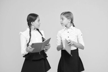 Dil eğitimi. Sevimli çocuklar ders kitabı ile çalışır. Okul çalışmaları için okuma becerilerini pratik edin ve geliştirin. Okul konseptine geri dönelim. Kızlar kitap tutar. Kız öğrenciler sarı arka plan üzerinde birlikte çalışma