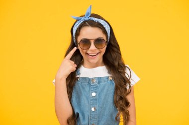 Neşeli görünüyorsun. Mutlu çocukluk. Güzel bir yaz tatili. Haidresser Salonu. Bahar çocuğu modası. Neşeli küçük kız sarı arka plan. Retro çocuk uzun saçı. Küçük kız. Güneş gözlüğü.
