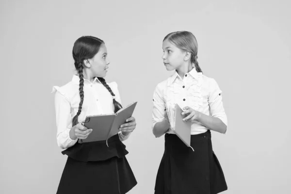 Étudier la langue. Les enfants mignons étudient avec un manuel. Pratiquer et améliorer les compétences en lecture pour les études scolaires. Retour à l'école. Les filles tiennent le livre. Les écolières étudient ensemble sur fond jaune — Photo