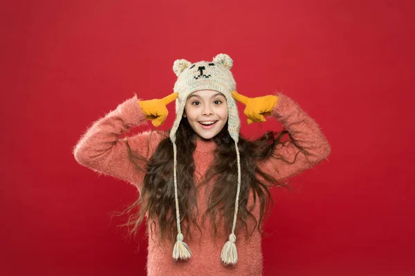 Winterkleding. Kleine jongen draagt gebreide hoed. Blijf warm. Meisje winter mode accessoire. Klein kind lang haar dragen hoed rode achtergrond. Schattig model genieten van de winter stijl. Teddy beer. Schattige beer zijn — Stockfoto