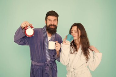 Bornozlu ve kupalı bir çift. Sakallı ve uykulu kadın ile adam sabah kahve veya çay tadını çıkarın. Uyanma ve güzel günler zamanı. Erkek kocası kahve ve saat tutuyor. Her sabah kahveyle başlar.