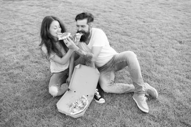 Hile yemeği. Yeşil çimenlikte dinlendirici pizza yiyen çift. Fast food teslimatı. Sakallı adam ve kız arkadaşı peynirli pizzanın tadını çıkarırlar. Aşık çift pizza ile açık havada kalma. Aç insanlar. Basit mutluluk