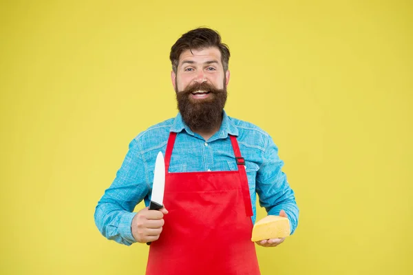 Laten we boterham maken. kaasmaker eigen bedrijf. hipster met baard in schort. Zuivelwinkel. Kaasfestival. Dieet en voeding. Een vrolijke man met een baard sneed kaas met mes. kaasmakerij — Stockfoto