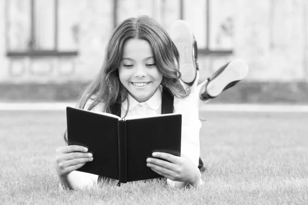 O conhecimento é mais do que informação. Menina pequena feliz ler livro na grama verde. Criança adorável obter conhecimento da leitura. Dia do conhecimento ou 1 de setembro. Teste o seu conhecimento escolar — Fotografia de Stock