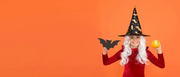 Enter at your own risk. Halloween child happy smile orange background. Witch child hold bat and pumkin. Little child wear witch hat and hair. Small child with Halloween look, copy space — Stock Photo, Image