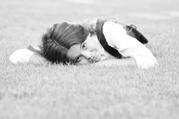 Прекрасный расслабленный вид. Очаровательная девушка со школьным взглядом отдыхает на зеленой траве. Милый маленький ребенок имеет школьный вид в формальной одежде. Внешний вид маленькой модной модели Vogue — стоковое фото