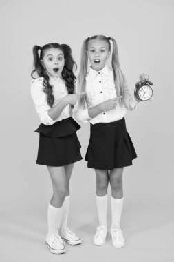 Retro zaman nedir? Şaşırmış küçük çocuklar sarı arka plan üzerinde retro saat işaret. Retro tasarım saati tutan açık ağız ile küçük kızlar. Retro tarzıvintage saat ile Adorbale çocuklar