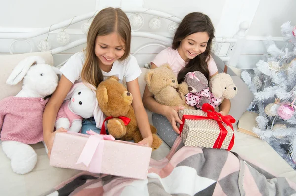 Magic moments. Small girls bed on Christmas eve. Happy children Christmas spirit. Small children in bedroom with gift. Kindness concept. Christmas atmosphere. Making surprise. Wrapped present