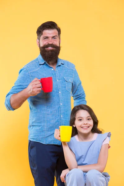 Padre e hija beben té en casa. Concepto de fiesta de té. Buenos días. Tomando café juntos. Equilibrio hídrico y salud. Té familiar. Barbudo hombre y feliz niña sosteniendo tazas —  Fotos de Stock