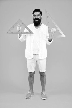 Geometrideki açıları ölçüyorum. Geometri öğretmeni okul dersi için turuncu arka plan üçgenleri tutuyor. Hippi öğrenmesi ya da geometri öğretmesi. Geometride geometrik aletler kullanan sakallı adam