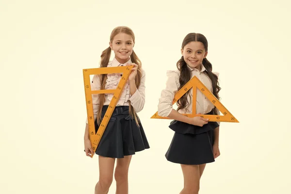 Se aprende una lección. Niños pequeños con instrumentos de medición en la clase escolar. Niñas preparándose para la lección de geometría. Lindas colegialas sosteniendo reglas triangulares para la lección —  Fotos de Stock