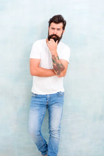 Confiante na sua escolha. Verão simples e casual. Parede cinzenta macho brutal. brutalidade temperamental masculina. Homem barbudo irradia masculinidade. atratividade física. jeans hipster bonitos. tendências da moda masculina — Fotografia de Stock