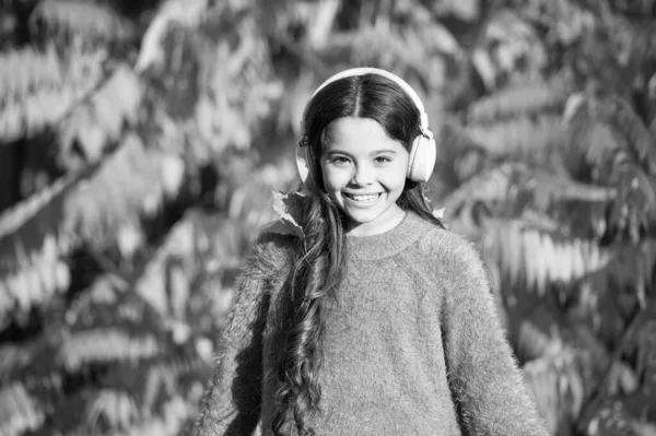 Musik för höststämning. Ung flicka avkopplande nära höst träd med hörlurar. Lyssnar på sång. Njut av höstens musik. Höstvandringar med fina låtar. Pedagogiska och nedladdningsbara ljudböcker för barn — Stockfoto