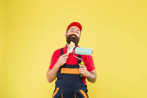 Mann bärtige Arbeiter Malerei. Reparatur und Renovierung. Bauarbeiter halten Farbroller und Pinsel in der Hand. perfekte Oberflächenbemalung. Vinylfarbe auftragen. Pick-Ups. Malwerkzeug. Pinselwalzenmaler — Stockfoto