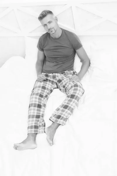Pajamas for home relax. Good morning. Guy happy sit on bed. Comfortable relax. Smiling guy wear pajamas at home. Handsome man enjoy his perfect morning. Menswear pajamas. Mature man model in bedroom