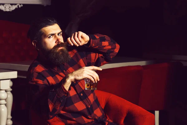 髭の男ヒップスターが赤い椅子にウイスキーのグラスを持ち — ストック写真