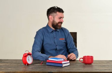 Sakallı adam beyaz arka planda defter tutuyor.