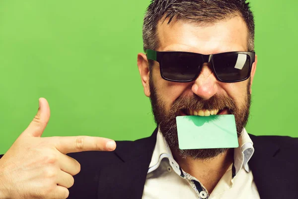 Человек с темной бородой держит зеленую визитку в зубах — стоковое фото