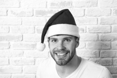 Beyaz tuğla duvar üzerine kırmızı santa şapka adam gülümseme