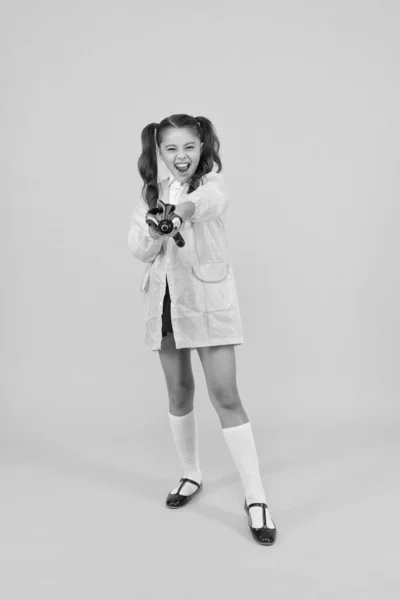 Sempre preparado para o inesperado. Criança pequena com aparência feliz. Menina com olhar de outono no fundo amarelo. Criança bonito com aparência elegante em capa de chuva com guarda-chuva. Conforto e olhar escolar — Fotografia de Stock