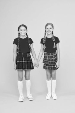 güven konsepti. eğitim konsepti. geri okula. bilgi günü. çocukluk mutluluğu. çocuk moda. Dostluk ve kardeşliği. okul üniforması mutlu kızlar. sarı arka planda akıllı küçük kızlar