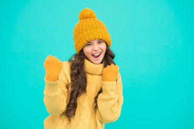 Kendini güçlü ve enerjik hissediyor. Çocuklar için kış aktivitesi. Küçük kız neşeli ruh hali, mavi arka plan. Küçük çocuk oynamaya hazır. moda ve güzellik. Sıcak örgü elbiseler ve aksesuarlar.