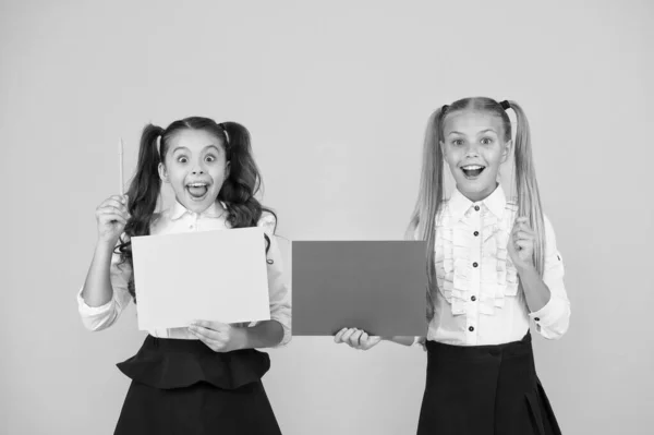 Geniale schooltips. Kleine leerlingen hebben ideeën. Kleine meisjes met pennen en papier op gele achtergrond. Kleine schoolkinderen met aantekeningen. Kleine kinderen maken presentatie voor les, kopiëren ruimte — Stockfoto