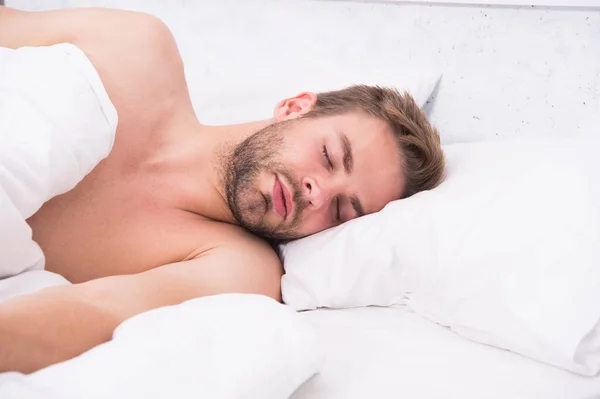 Circadiaan ritme reguleert slaap wake cyclus. Een knappe, ongeschoren man in bed. Genoeg slaap elke nacht. Tips slapen beter. Een man met baard ontspant zich op het kussen. Zacht kussen. Gezondheidszorgconcept — Stockfoto