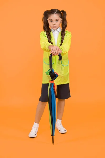 Estudante bonito se sentir protegido para o clima de primavera. Conceito impermeável. Combine sua capa de chuva com guarda-chuva. A estudante usa capa de chuva. Pequena estudante usar roupas resistentes à água para dia chuvoso — Fotografia de Stock