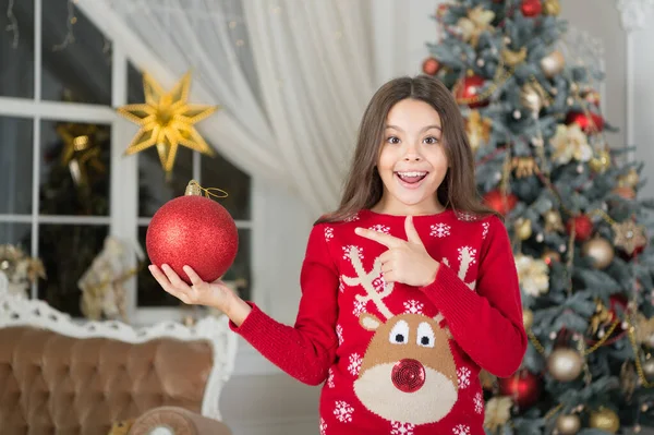 Rött är min favorit. Julinredning. En liten flicka nära julgranen. Barn firar jul hemma. Vintertraditioner. Förtjusande upphetsad unge bär jultröja. Begreppet presentbutik — Stockfoto