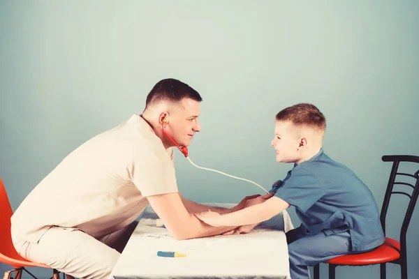professional talk. medicine and health. small boy with dad play. Future career. nurse laboratory assistant. family doctor. happy child with father with stethoscope. father and son in medical uniform