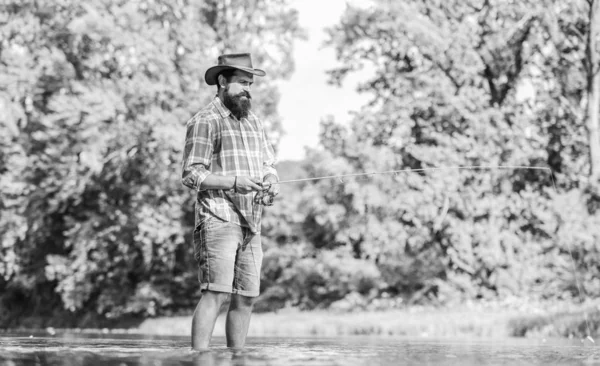 Ambiente tranquilo y pacífico. Una meditación amable. Peces normalmente capturados en estado salvaje. Granja de truchas. Pescador solo de pie en el agua del río. Hombre pescador barbudo. Equipo de pesca del pescador. Hobby actividad deportiva — Foto de Stock