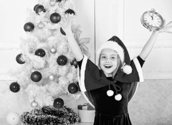 Last minute new years eve plans that are actually lot of fun. New year countdown. Girl kid santa hat costume with clock excited happy face counting time to new year. Last minute till midnight