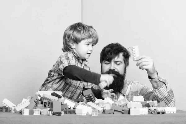 Father son play game. Dad and kid build of plastic blocks. Father and son create colorful constructions with bricks. Child care development and upbringing. Bearded father and boy play together